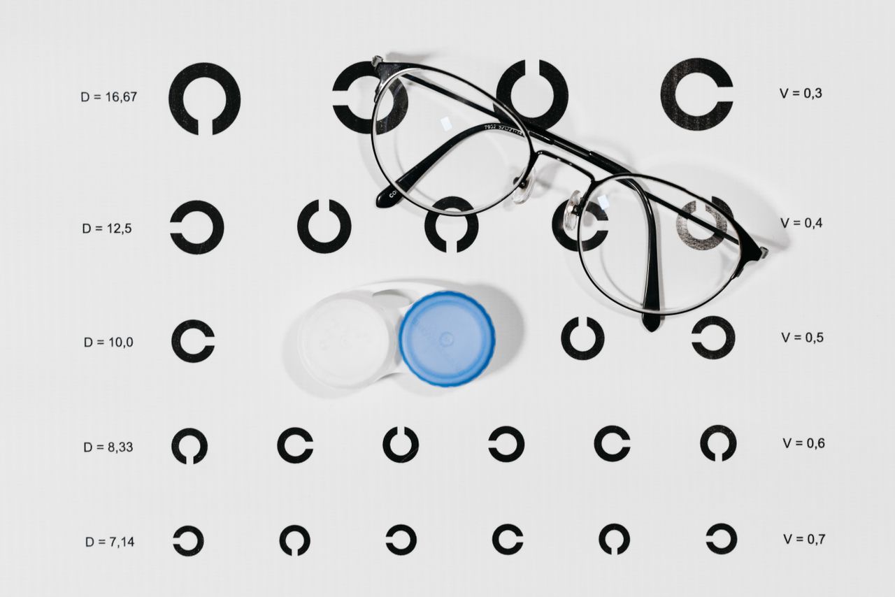Mastering the First Impression: Your intriguing post title goes here Close-up image of eyeglasses and contact lens case on a Snellen eye chart for vision testing.