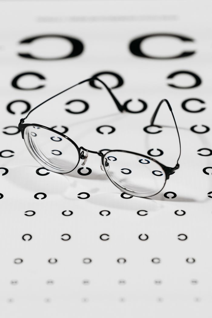 Eyeglasses resting on a Snellen eye test chart emphasizing vision correction and eye care.